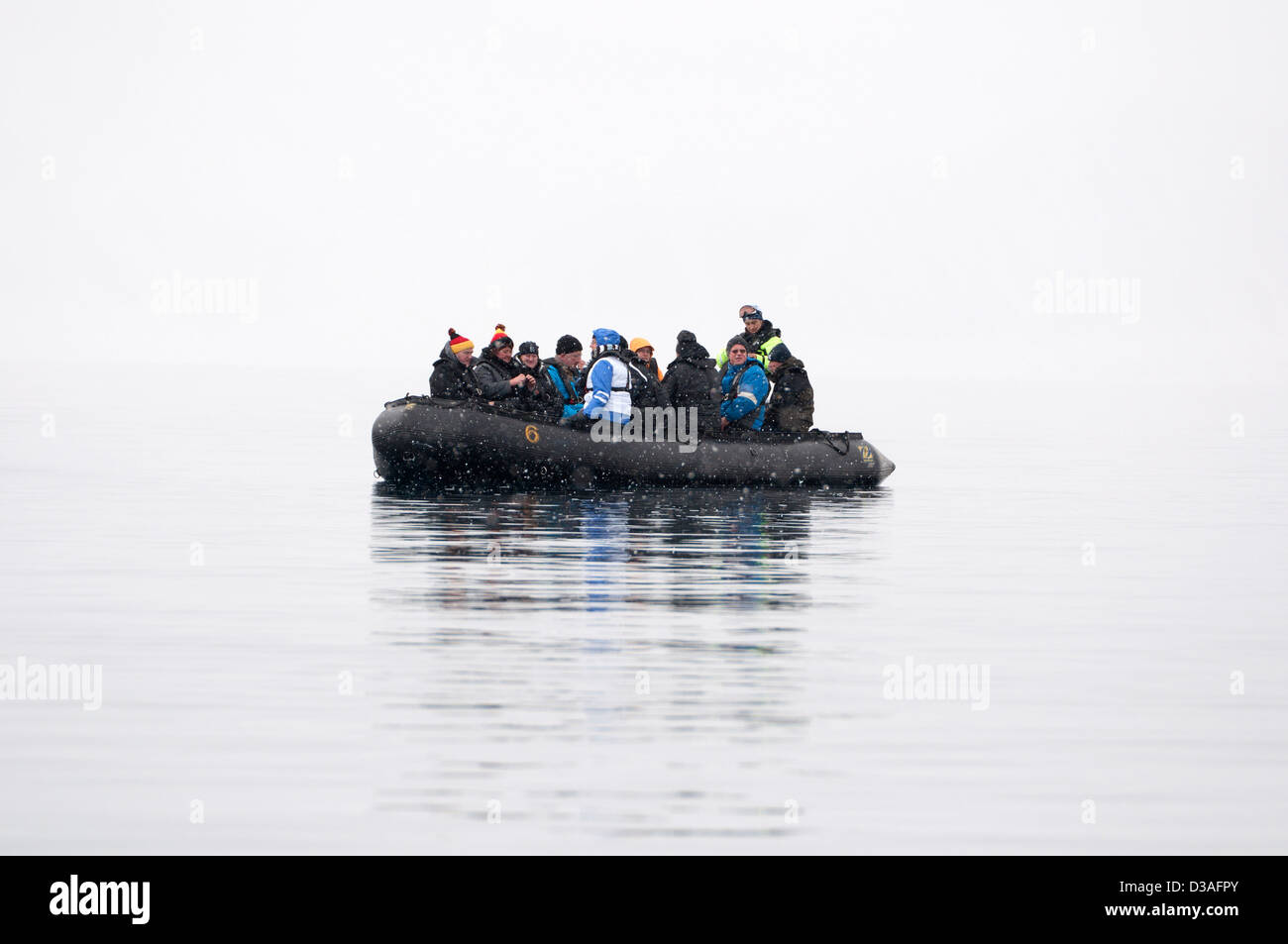 Tourists in a small zodiac exploring the misty fjords of Arctic Spitsbergen, Svalbard Stock Photo