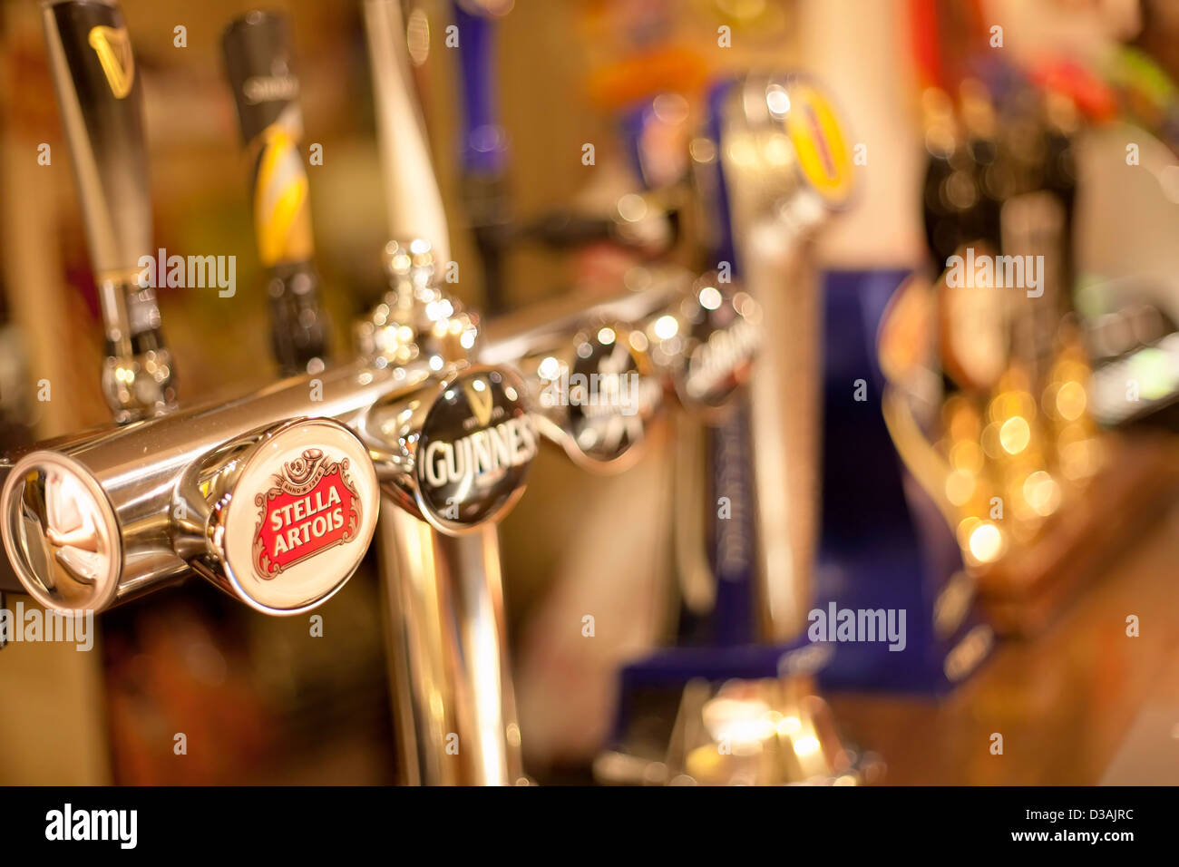 Pub bar, alcohol, taps, lager, Stella Beer pumps,  beer, lager, beer taps, public house, pub, bar, draught beer, draught pumps, beverages, alcoholic Stock Photo