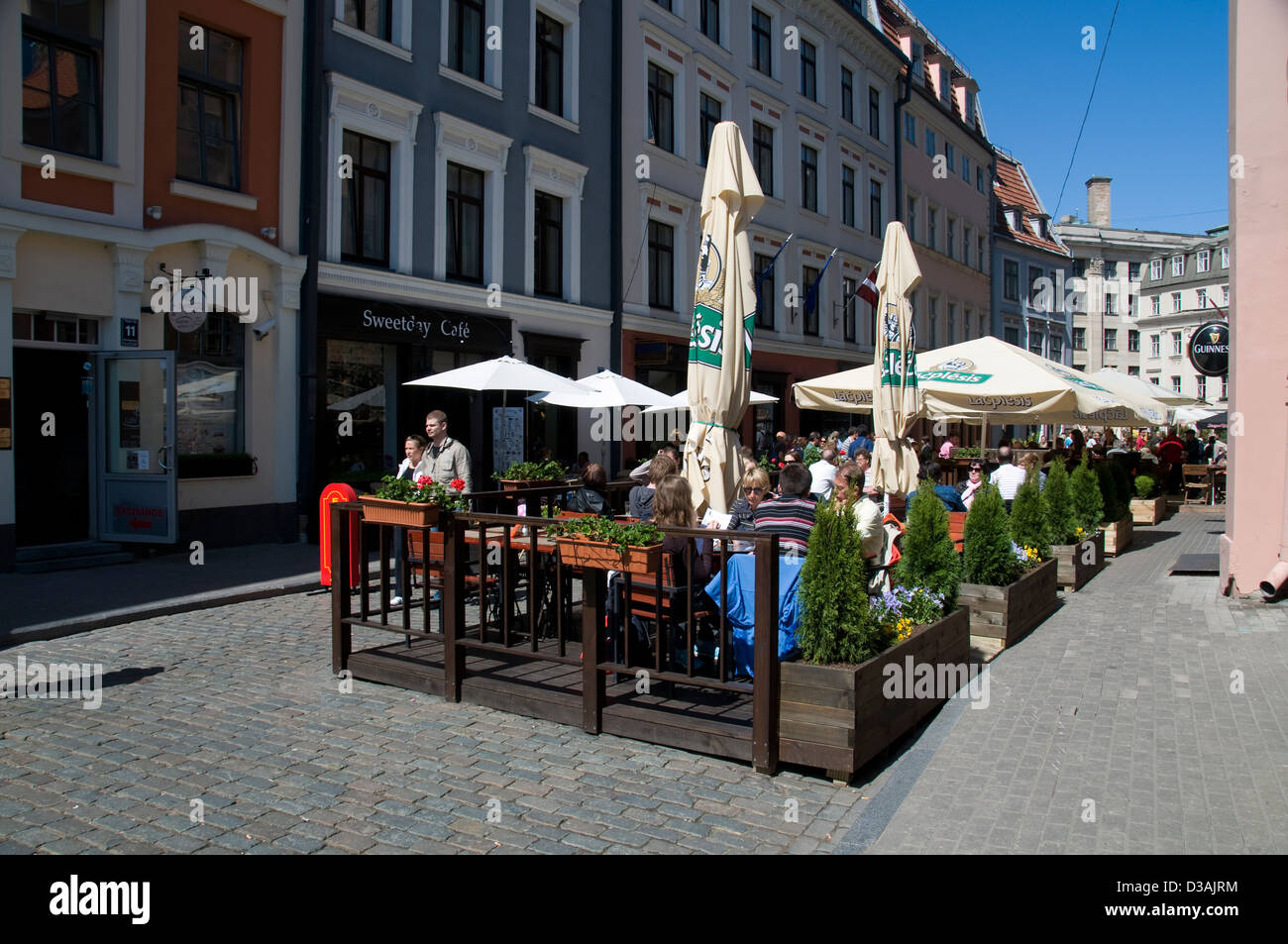 Visitors having lunch at an outdoor platform restaurant on Tirgonu iela, Riga old town, Riga, Latvia, Baltic States Stock Photo