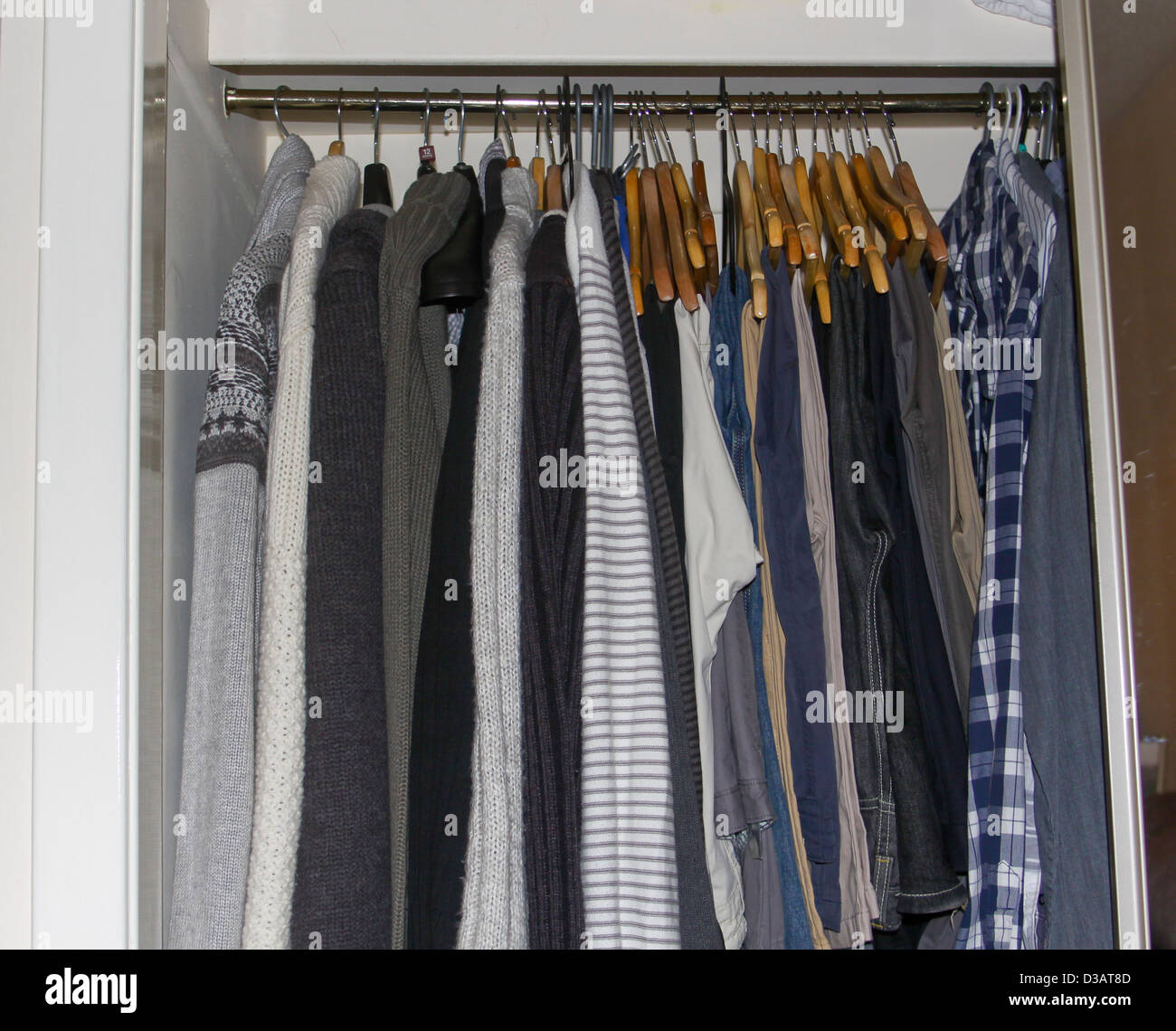 Mens Jumpers trousers and shirts hanging in wardrobe Stock Photo