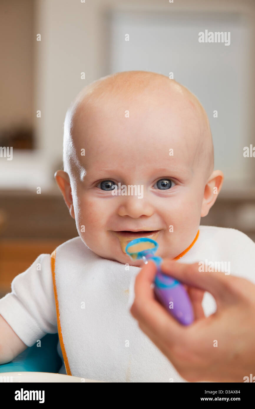 Caucasian mother feeding baby in high chair Stock Photo Alamy