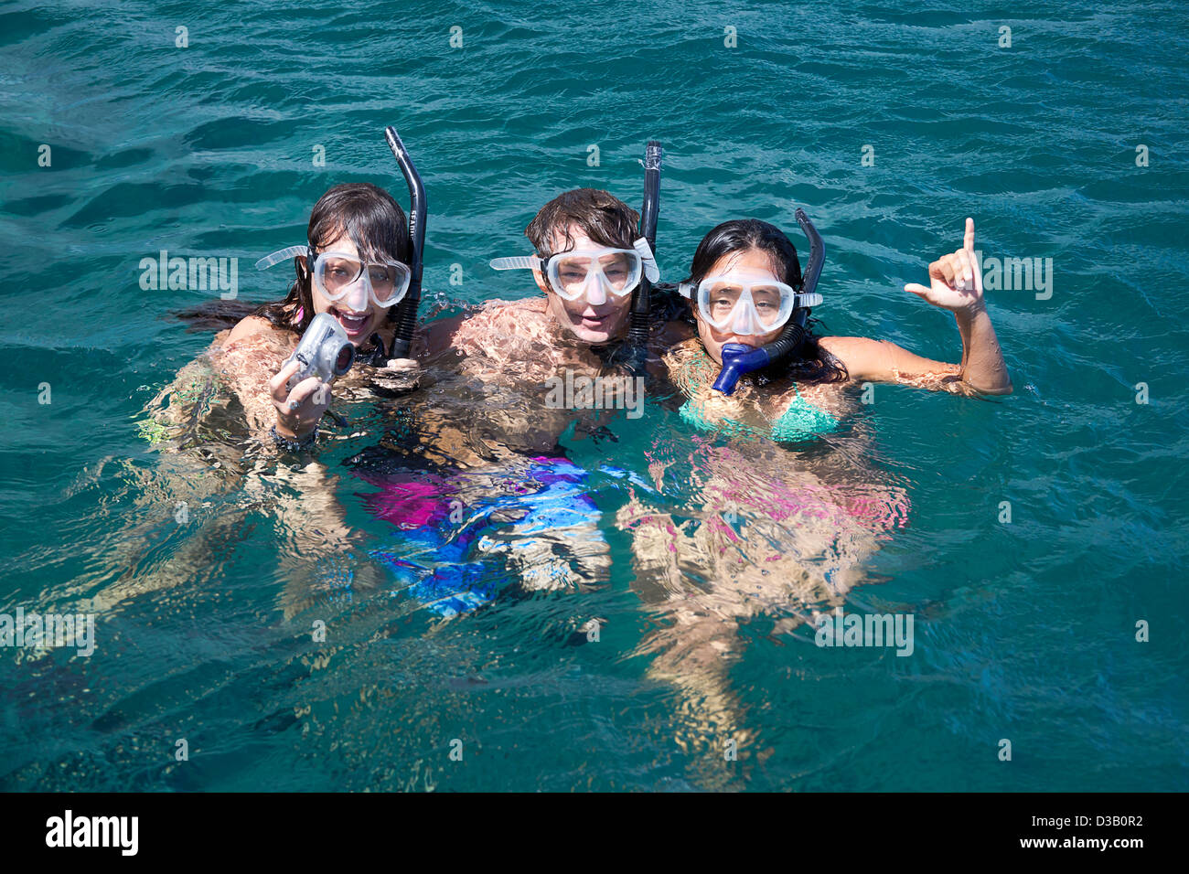 Three young snorklers (MR) free diving off the island of Lanai with an underwater digital camera, Lanai, Hawaii. Stock Photo