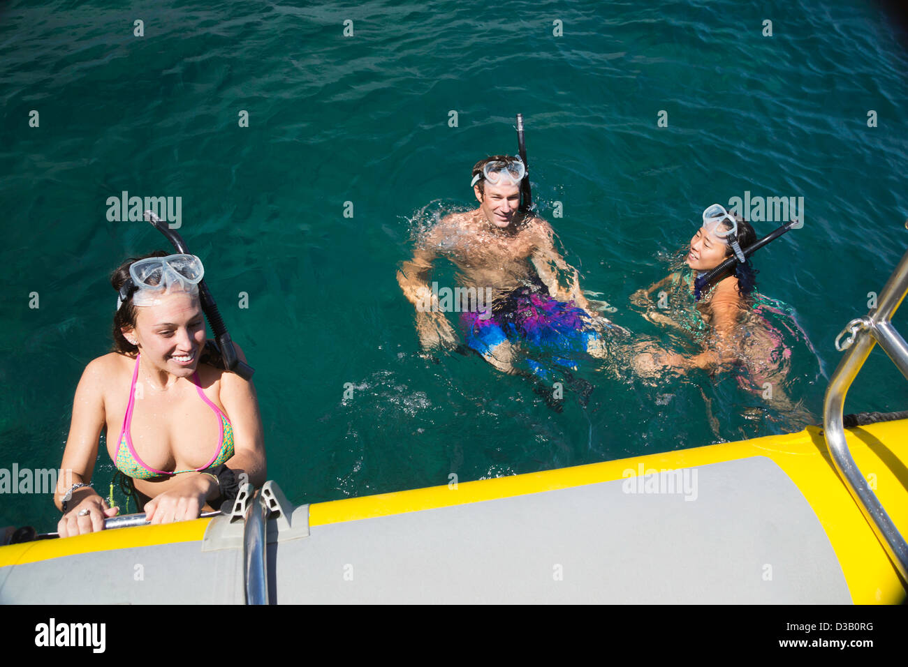 Three young snorklers (MR) free diving off the island of Lanai, return to thier charter boat, Lanai, Hawaii. Stock Photo