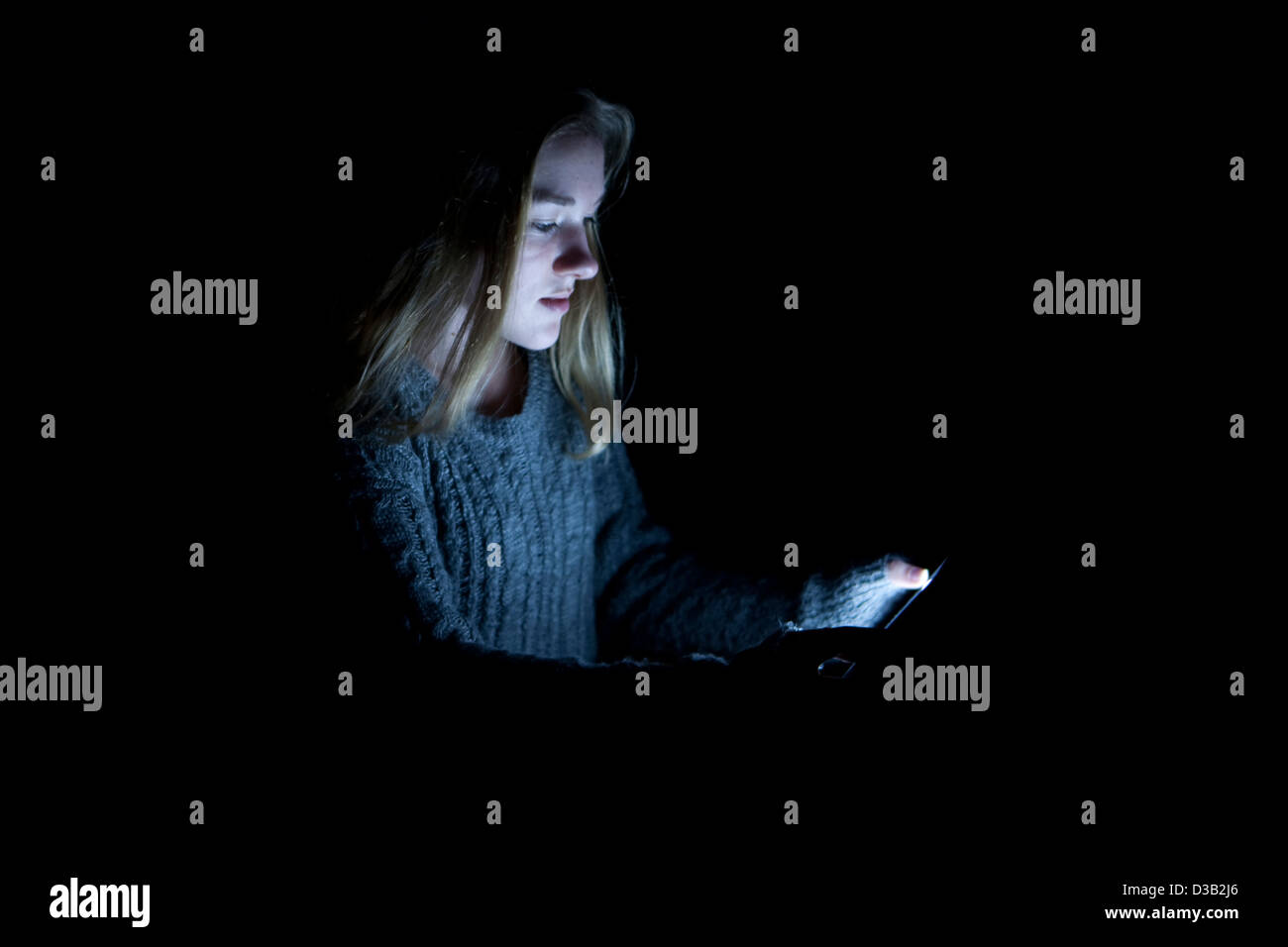 Girl with her Ipad in a dark room. Stock Photo