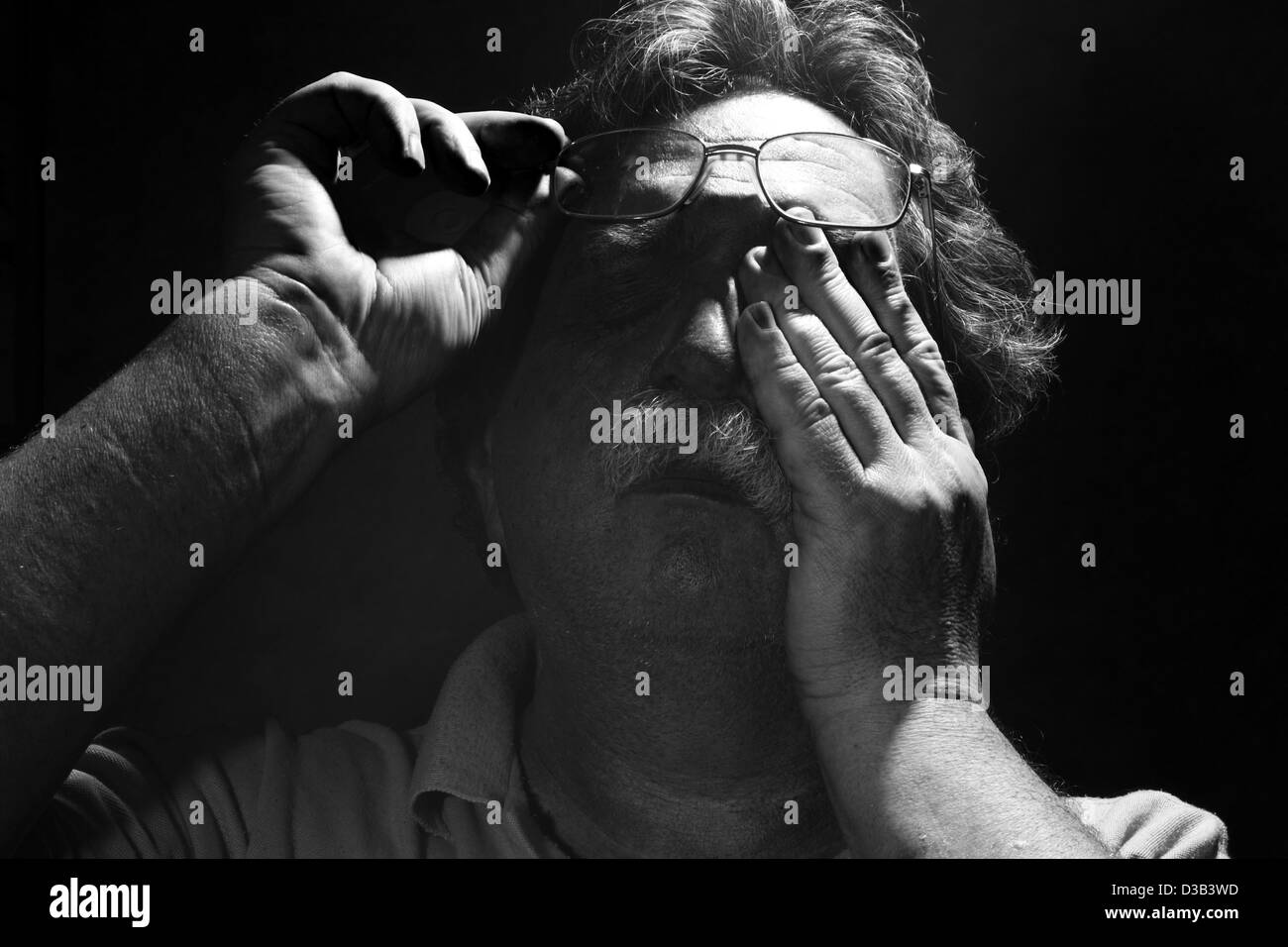tired middle-aged man rubs his eyes, black and white Stock Photo
