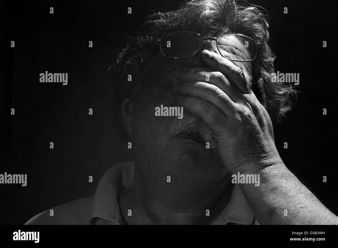 tired middle-aged man rubs his eyes, black and white Stock Photo