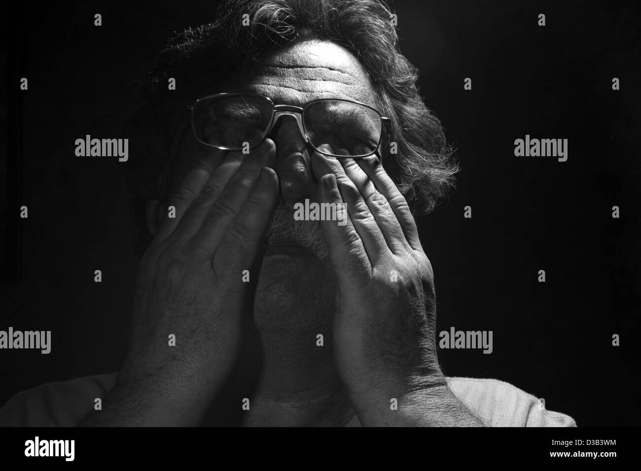 tired middle-aged man rubs his eyes, black and white Stock Photo