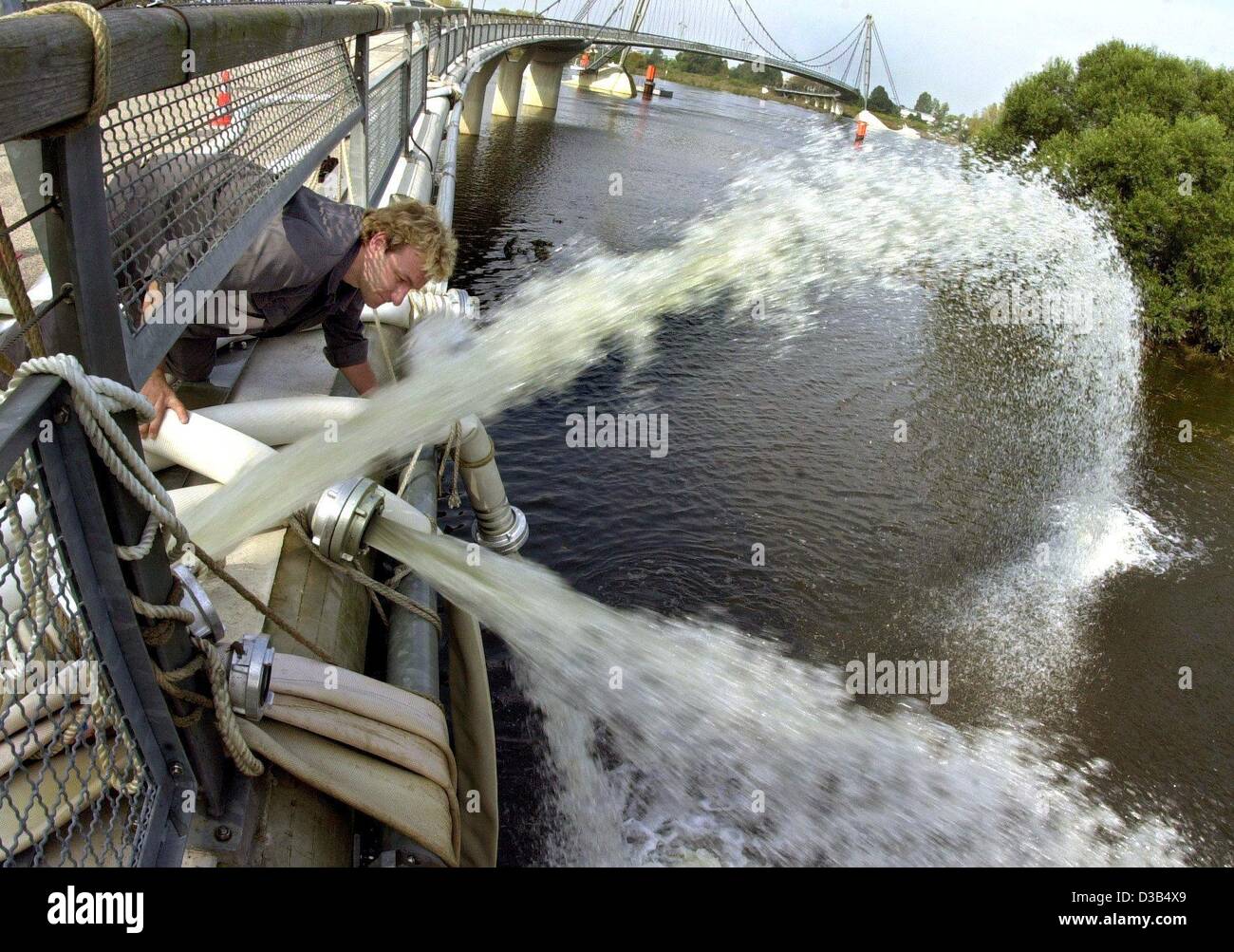 (dpa) - A helper of the Technisches Hilfswerk (Technical Helpers' Organisation) checks the hoses, through which the flood waters are pumped back into the river Elbe in Magdeburg-Herrenkrug, eastern Germany, 25 August 2002. Eastern parts of Magdeburg were flooded, drowning a hotel, a race track and a Stock Photo