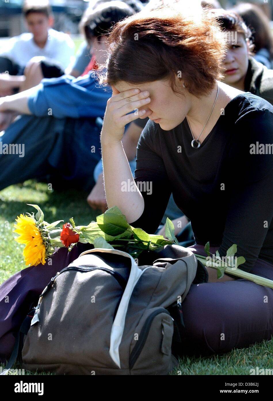 (dpa) - A woman with a sunflower and a rose on her knees sits on a lawn to commemorate with others the victims of the 11 September terror attacks, Berlin, 11 September 2002. The memorial service in the Cathedral in Berlin was transmitted on screens outside. On the first anniversary of the attacks th Stock Photo