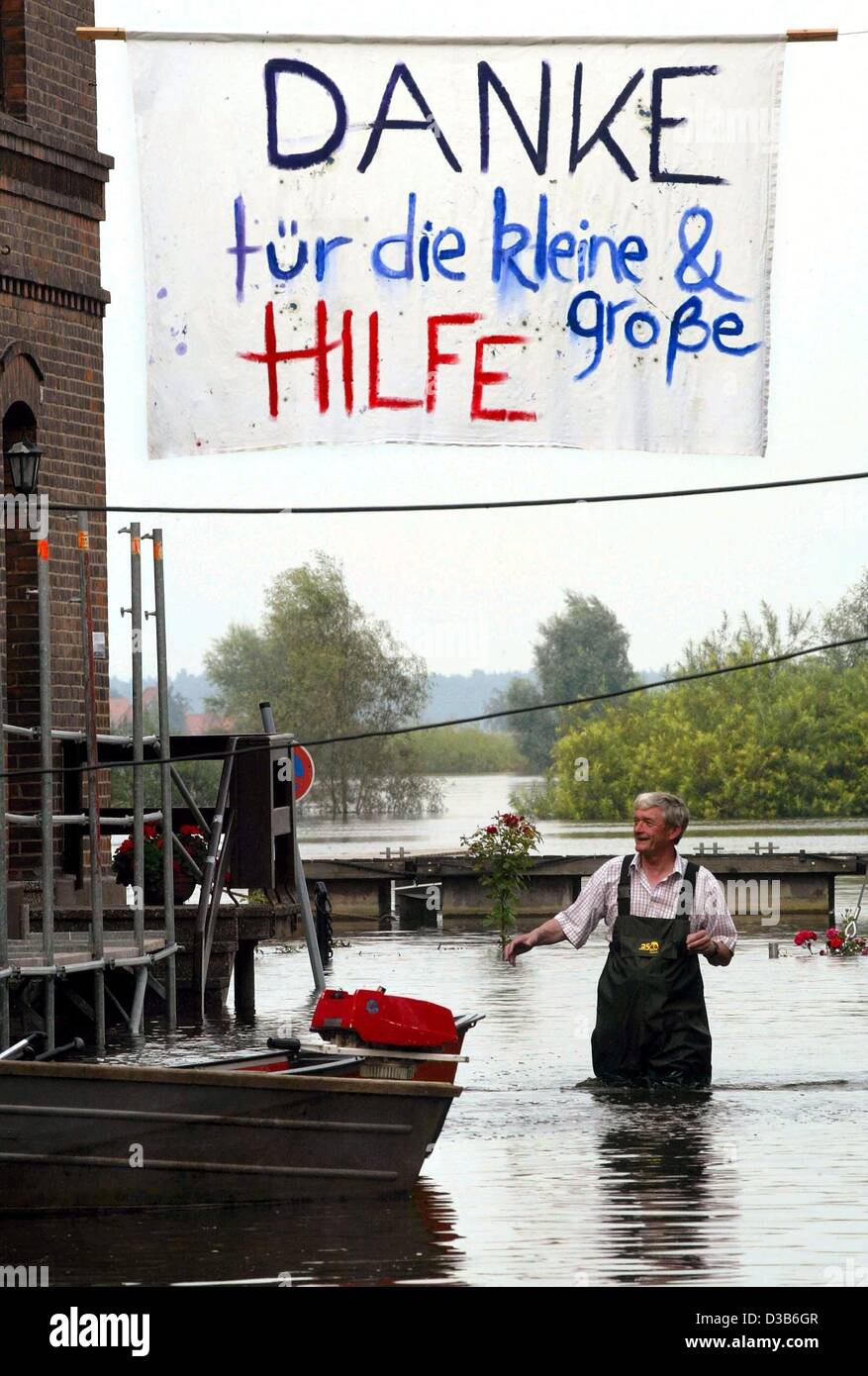 (dpa) - A resident wades through the floodwaters underneath a banner reading 'Danke fuer die kleine & große Hilfe' (Thanks for the small and big help) in the main street of Hitzacker, northern Germany, 24 August 2002. Helpers had assisted to protect the historic old town of Hitzacker from the flood. Stock Photo