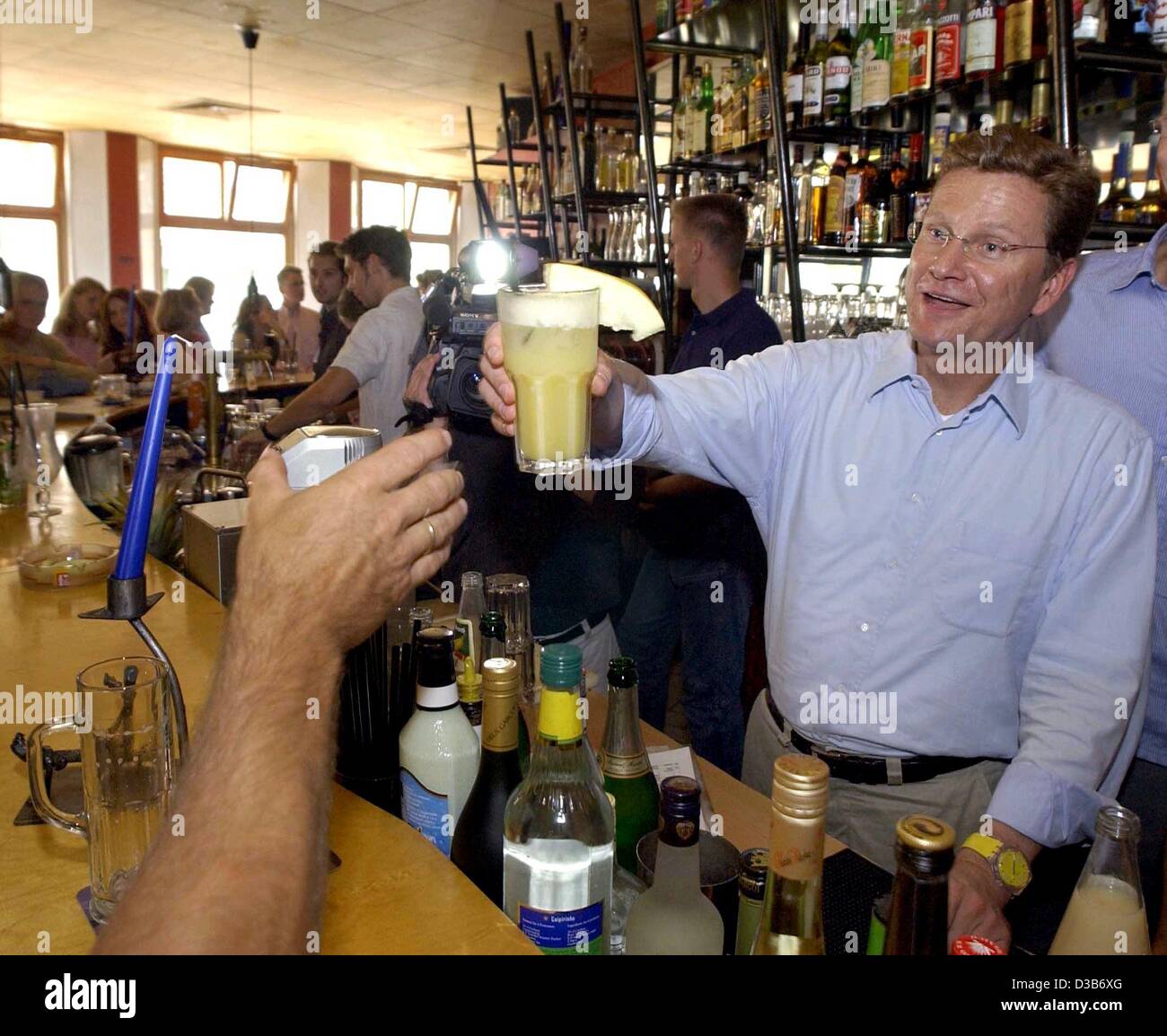 (dpa) - Guido Westerwelle, Chairman of the German liberal party FDP, serves as a barmixer to promote his election campaign programme in a student's cafeteria in Greifswald, Germany, 7 August 2002. For five weeks Westerwelle will tour the country in his trailer, the so called 'Guidomobil'. Stock Photo