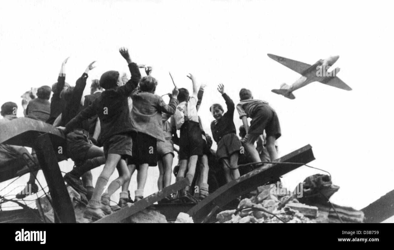 (dpa files) - Boys from West Berlin standing on a heap of rubble wave cheeringly to a US cargo plane that brings food to West Berlin, 1948. When the Soviets on 24 June 1948 blocked all traffic to and from the Western sectors, which were enclosed by the Soviet Zone, the Western Powers organized an ai Stock Photo