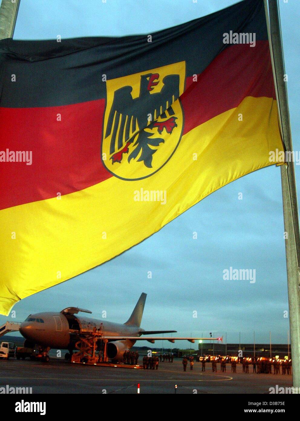(dpa) - The German flag is on half-mast as the coffins containing the bodies of the German soldiers arrive aboard an air force plane at the airport in Cologne, Germany, 25 December 2002. The seven German peacekeepers were killed in a helicopter crash on 21 December in Afghanistan. They served on the Stock Photo