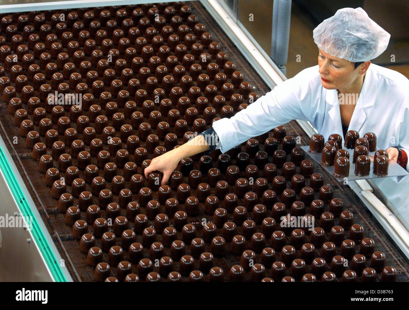 (dpa) - An employee checks the fabrication of 'chocolate kisses', a kind of chocolate marshmallows, at a production line of the sweets factory Grabower Suesswaren GmbH in Grabow, Germany, 26 November 2002. The company has an annual turnover of some 100 million Euro. Stock Photo