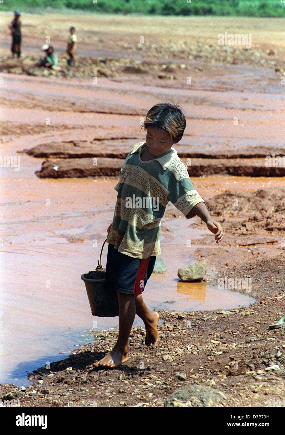 (dpa) - A boy carries a bucket of water along the banks of a river in which tin is washed, near the village of Hin Bun Ban Bon-Nai, Laos, October 2002. Laos is one of the world's poorest countries. Children often have to work or are forced to prostitution. They are often violently abducted from thei Stock Photo