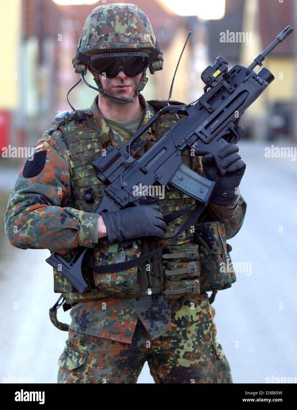 A soldier equipped with hi-tech weapon prototype is aiming at a target through a laser sight mounted on his gun in Hammelburg, Germany,  9 December 2002. The 'infantryman of the future' carries  communication aerials and a satellite navigation system. Though his vest is heavily armoured it's weight  Stock Photo