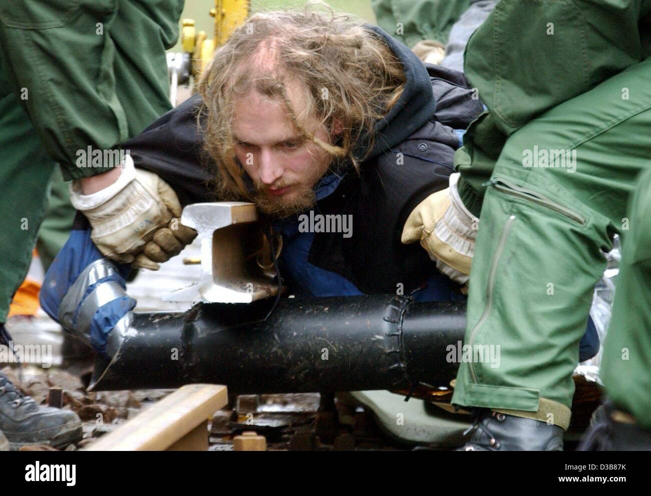 (dpa) - Policemen remove a protestor against the current nuclear waste transport who has chained himself to a steel tube that was dug underneath the tracks near Leitstade, Germany, 13 November 2002. It was only after two hours that police managed to end the blockade. With a load of 1,320 tons it is  Stock Photo