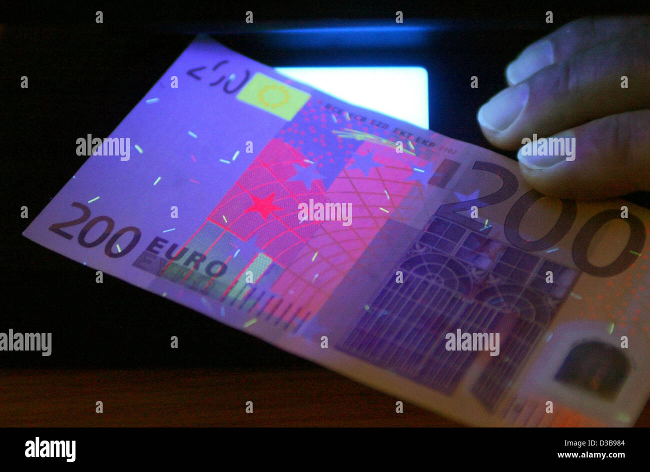 (dpa file) - The picture dated 30 November 2004 shows a counterfeited 200-euro bill under an ultraviolet lamp at a police station in Magdeburg, Germany. Stock Photo
