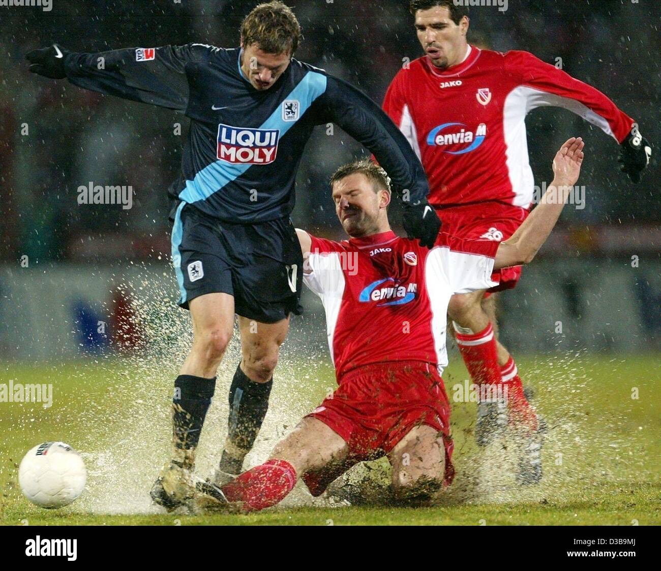 (dpa) - Cottbus' Polish defender Andrzej Juskowiak (C) kicks the ball away from Munich's forward Benjamin Lauth (L), Cottbus, 30 November 2002. In the background: Cottbus' forward Paulo Rink. In a very rainy match TSV 1860 Munich beats FC Energie Cottbus 4-3. Stock Photo