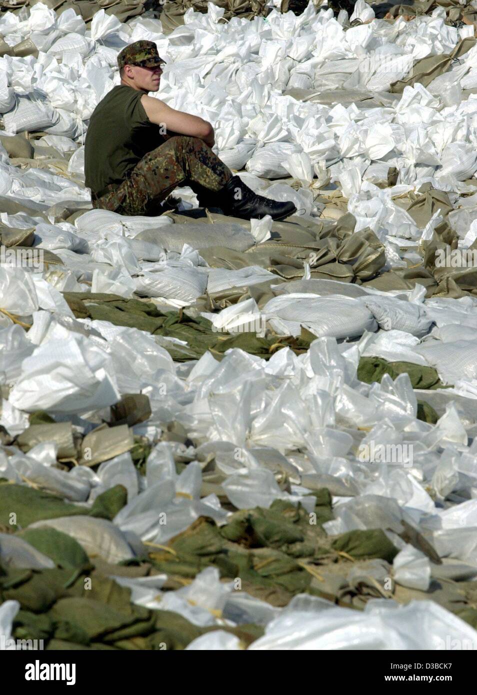 (dpa) - A German soldier is resting on a bunch of sandbags near Lauenburg, 20 August 2002. As the floodwaters of the Elbe River are surging northwards the region of duchy Lauenburg is especially endangered. If the dike there breaks the high water could flow nine kilometres into the hinterland affect Stock Photo