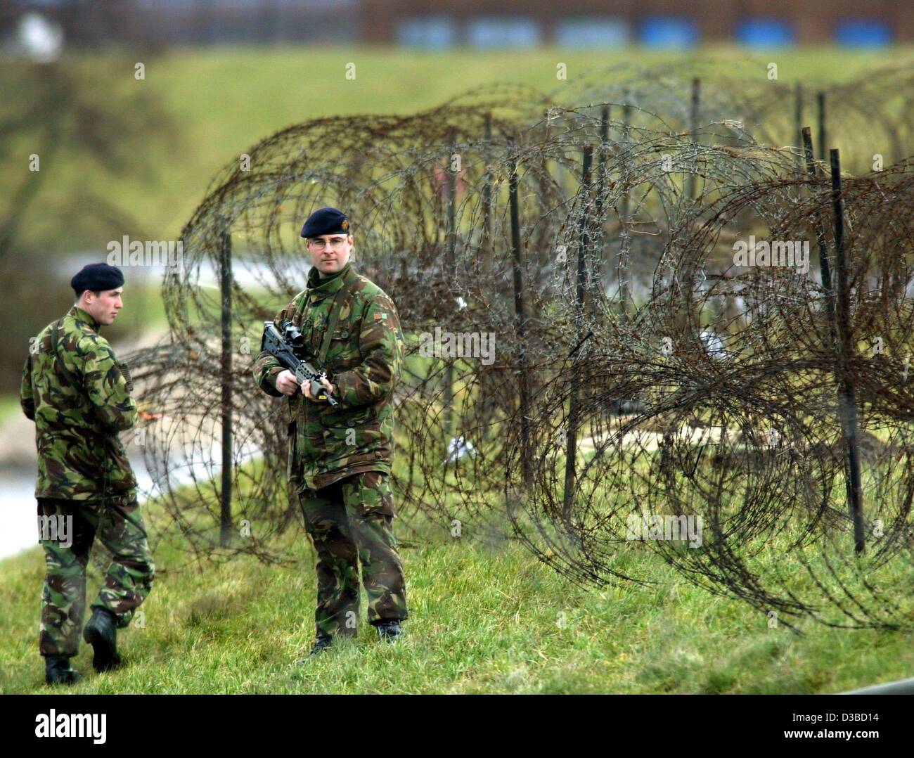 (dpa) - Two British soldiers patrol along the barbed wire on the dyke of the harbour in Emden, northern Germany, 29 January 2003. From here, British tanks will be shipped to the Gulf region next week. The British army has chartered 36 ships to relocate equipment to the Gulf region. All of the ships  Stock Photo