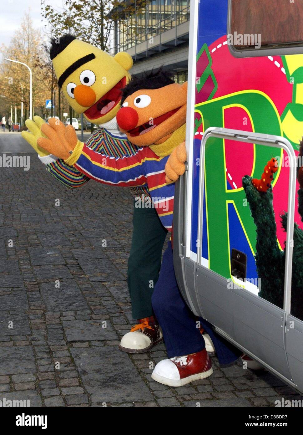 (dpa) - Ernie (R) and Bert (L) look past the back of the Sesame Street tour bus and wave their hands in Hamburg, 27 November 2002. The first season of the German edition was broadcast in January 1973. On the occasion of the 30th Birthday of Sesame Street, Ernie and Bert visit celebrities on a benefi Stock Photo