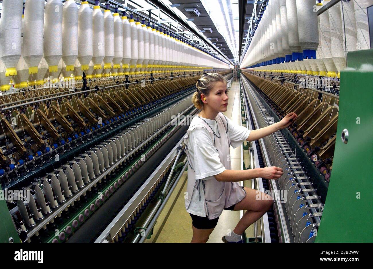 (dpa) - A worker stands next to a 70m long spinning machine in a spinning company in Hohenfichte, Germany, 22 January 2003. In this factory, cotton for outerwear, bed-linen and technic textiles are produced. Stock Photo