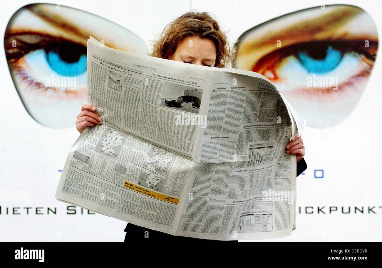 (dpa) - Big eyes staring from an advertisment seem to watch a young woman as she reads her newspaper in Frankfurt, 22 January 2003. Stock Photo