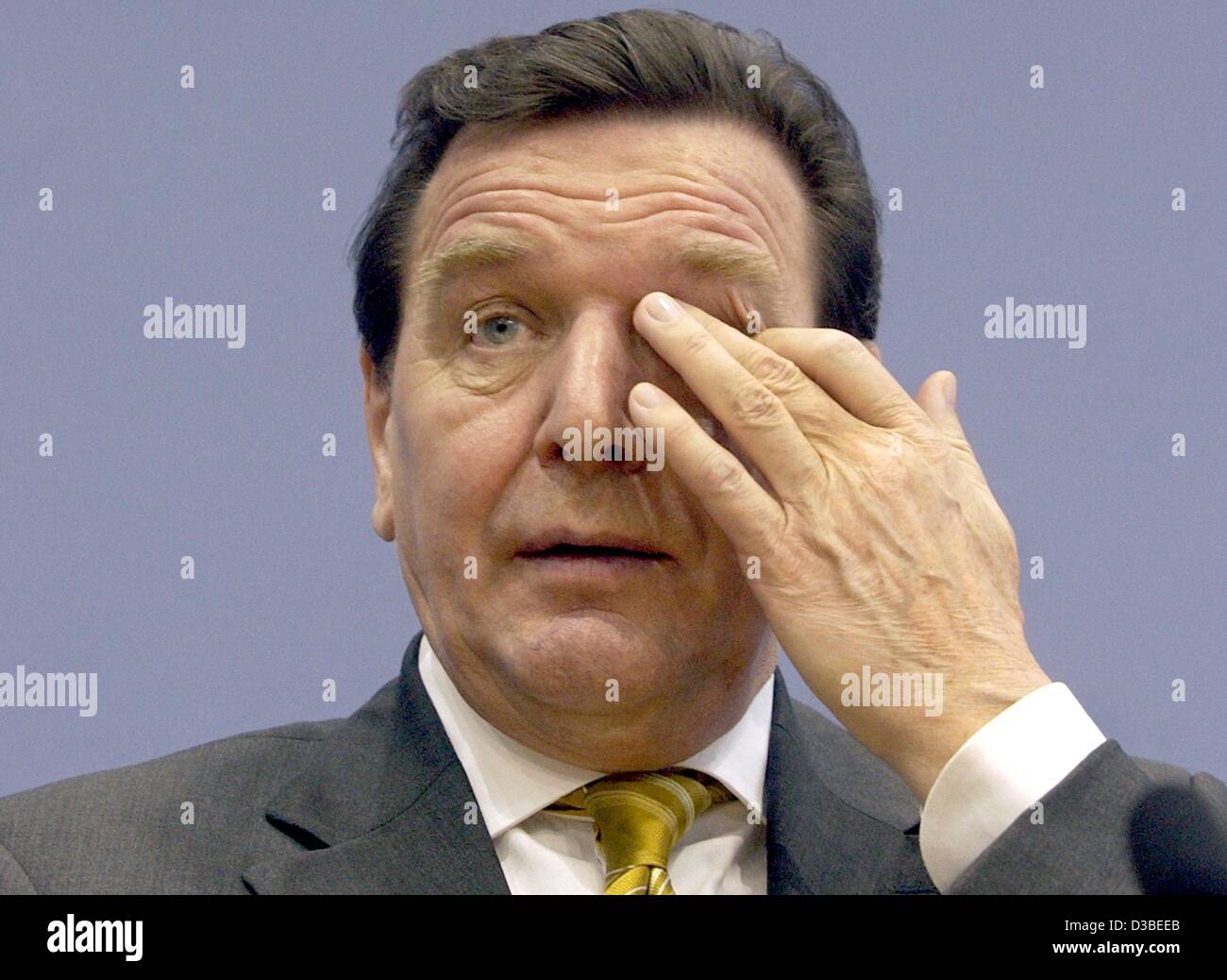 (dpa) - German chancellor Gerhard Schroeder (SPD) is scratching his eye during a press conference, Berlin, 14 January 2003. Against common expectation Schroeder does not expect higher indebtedness for the federal budget in 2003. Half a percentage point less economic growth would result in only one b Stock Photo