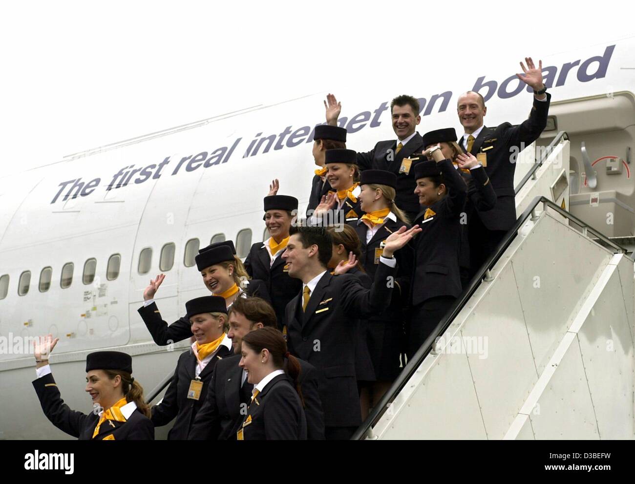 (dpa) - Lufthansa cabin staff are standing and waving on the steps to a Boeing 747-400 labelled with the slogan 'The first real internet on board', Frankfurt, 15 January 2003. Lufthansa is the first airline to be testing a fast access to the internet for passengers. This is offered on scheduled flig Stock Photo