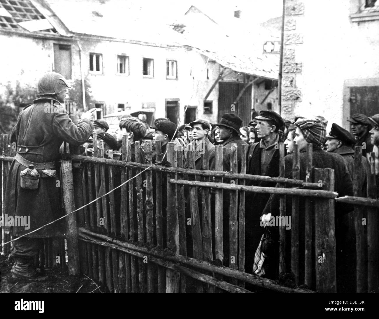 (dpa files) - A US soldier informs the inhabitants of a German village about the instructions passed by US commander-in-chief Eisenhower, in Germany, 1945. After the invasion of the Allies in Normandy on 6 June 1944 the downfall of the German Reich was doomed; the surrender of Nazi Germany on 8 May  Stock Photo