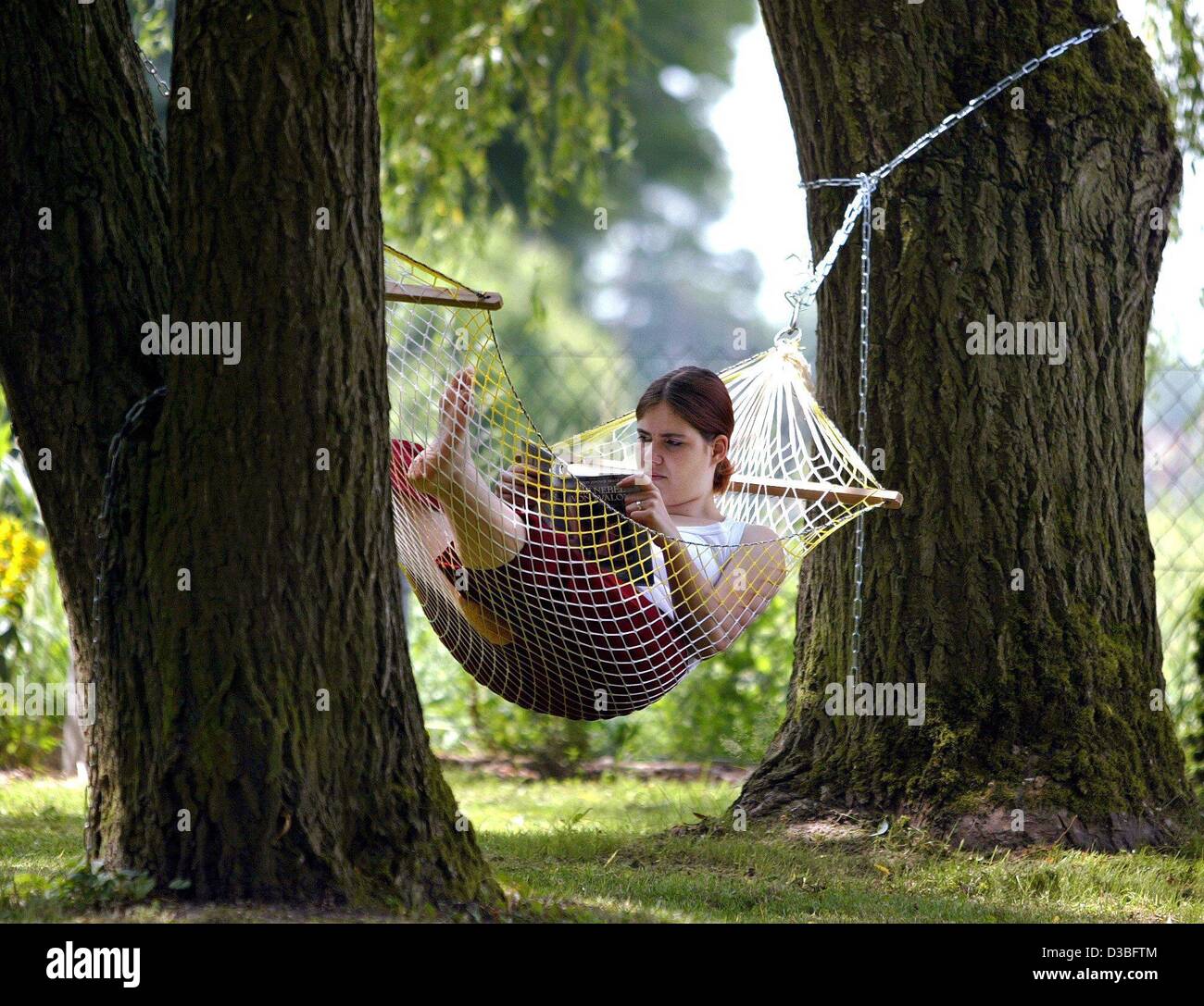 (dpa) - A young woman is reading a book while lying in a hammock ...