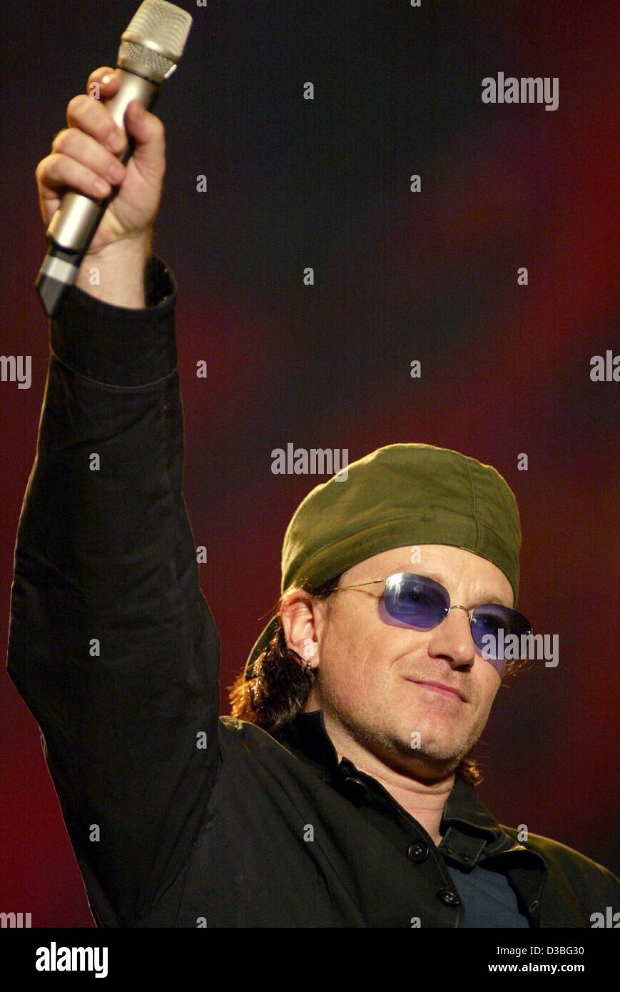 (dpa) - Bono, singer of the Irish rock band U2, holds a microphone in his hand and waves during his performance at the '10th Pavarotti and Friends' charity concert in Modena, Italy, 27 May 2003. Stock Photo