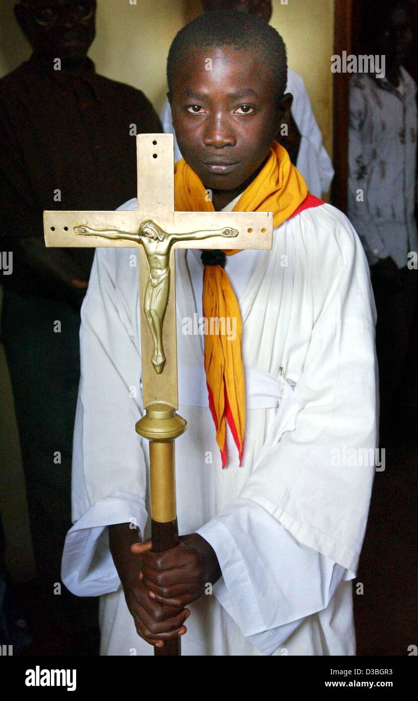 (dpa) - Congolese altar boy Martin Lokana wears a white gown and holds a crucifix in his hands in the Nyakasanza church in Bunia in the Democratic Republic of Congo, 15 June 2003.The German government on 13 June approved sending 350 non-combat troops to take part in a European Union peace mission in Stock Photo