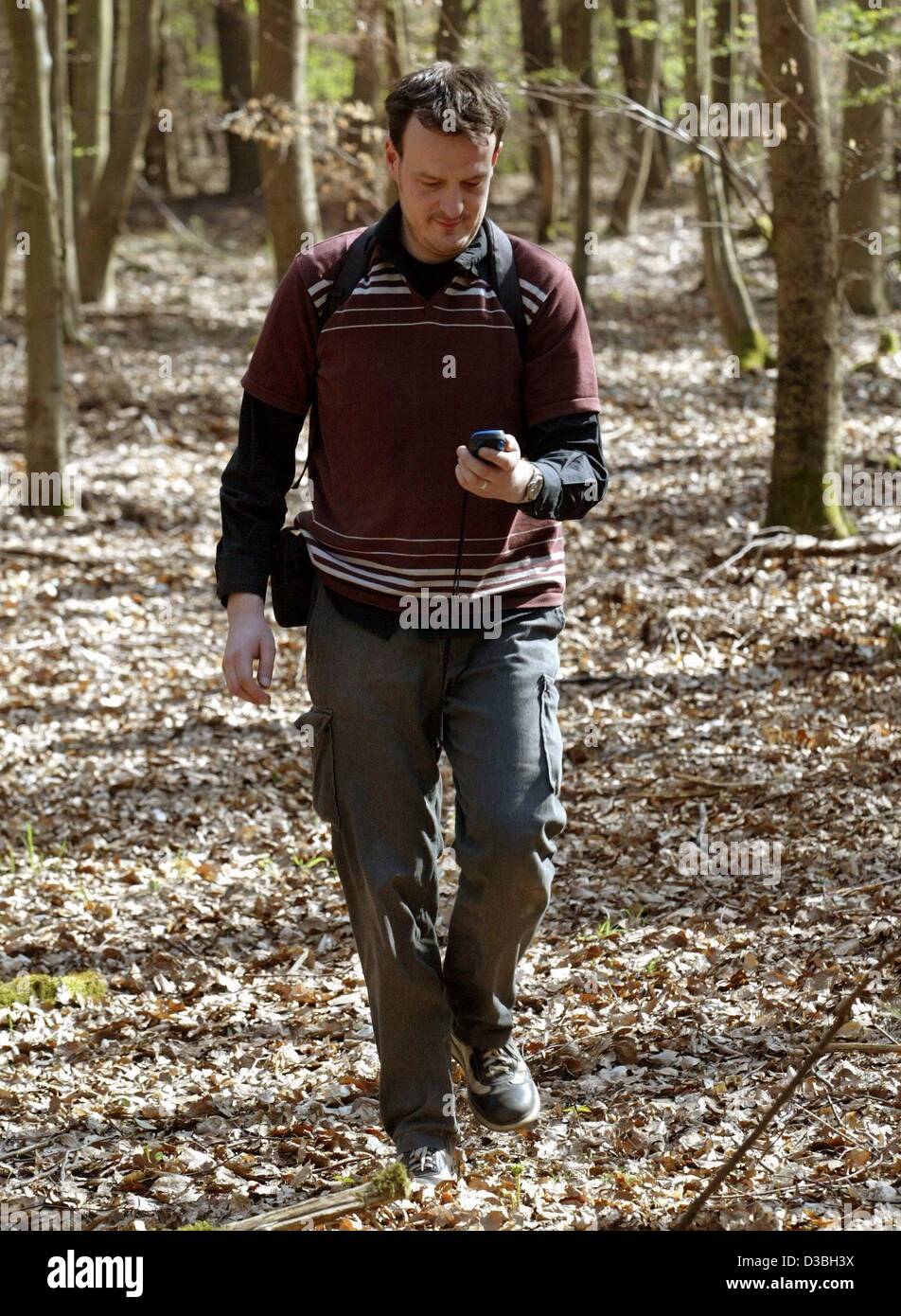 (dpa) - Geocoacher Axel Burgemeister walks through a forest trying to find the position of a 'treasure' published on the internet with a GPS system, in a forest near Hagenbach, Germany, 14 April 2003. Geocoaching is a new hobby for old and young people: both kids and grownups enjoy going on treasure Stock Photo