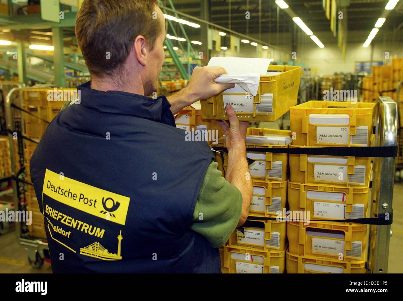 (dpa) - An employee of the Deutsche Post AG unloads a cart with yellow post bins at the letter center (Briefzentrum) in Duesseldorf, Germany, 27 January 2003. The company has 83 national letter centers and an international post center. Daily about 72 million letters are sorted and mailed. Stock Photo
