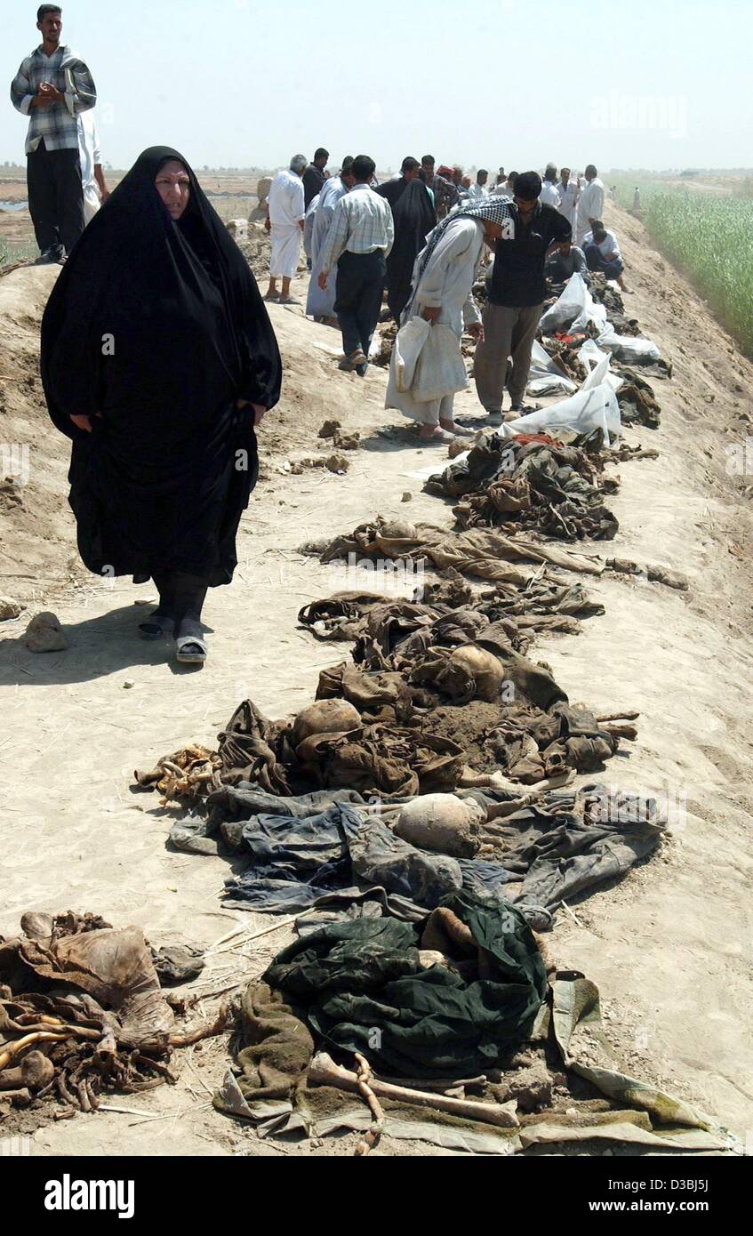 (dpa) - Iraqis are looking at human remains lined up near the village of Al Findiya, 80 kilometres south of Baghdad, 7 May 2003. Residents had dicovered the mass grave on 2 May and dug out the remains. Several thousands of people are believed to have been killed by the Republican Guard after a faile Stock Photo