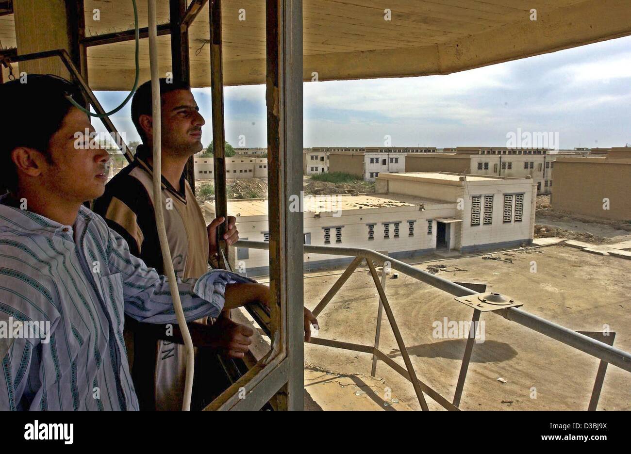 (dpa) - Two Iraqis stand on the watchtower and look across the premises of the infamous Iraqi state security prison Abu Ghraib around 30 kilometres west of Baghdad, Iraq, 2 May 2003. Thousands of political prisoners had been tortured and executed in the prison. Stock Photo