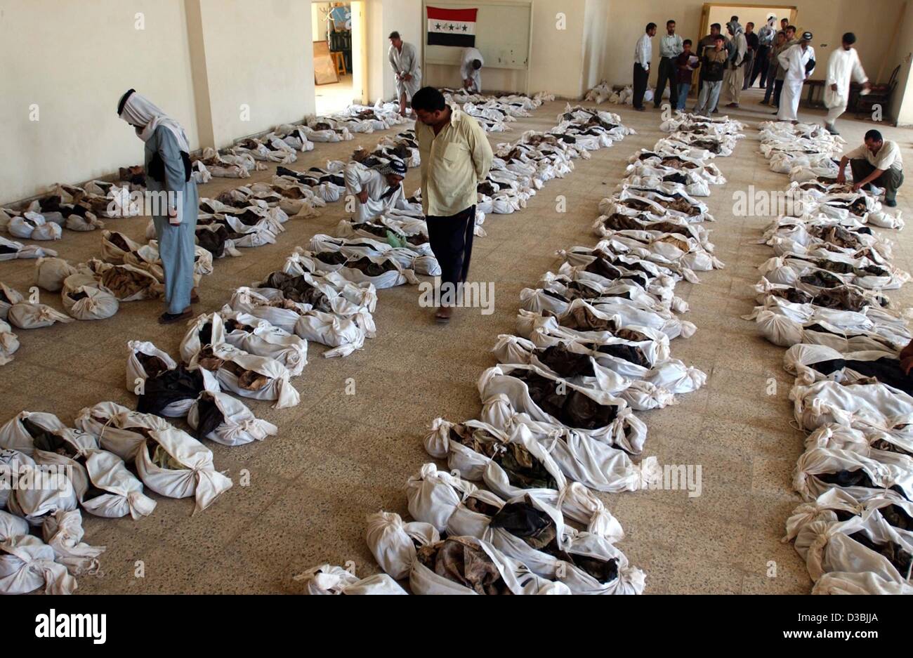 (dpa) - Iraqis walk between hundreds of bodies found in a mass grave 50km south of Baghdad and displayed for identification in the nearby town of Al-Mesayeb, Iraq, 24 May 20003. In central Iraq, Iraqis are trying to identify their loved ones whose bodies have been dug-up from several mass graves, wh Stock Photo