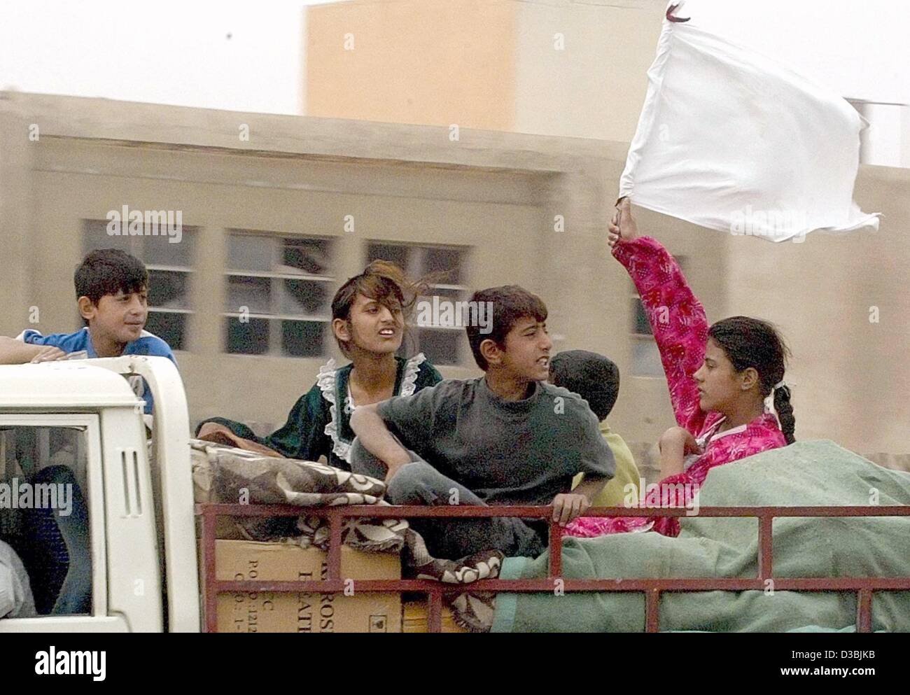 (dpa) - An Iraqi girl hangs up a white flag while sitting on her belongings in a truck in Baghdad, 13 April 2003. Stock Photo