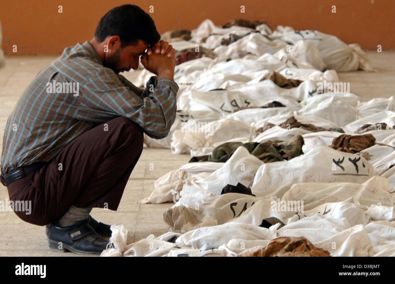 (dpa) - An Iraqi man rests as he checks a bag containing a body found in a mass grave 50km south of Baghdad and displayed for identification in the nearby town of Al-Mesayeb, Iraq, 24 May 20003. In central Iraq, Iraqis are trying to identify their loved ones whose bodies have been dug-up from severa Stock Photo