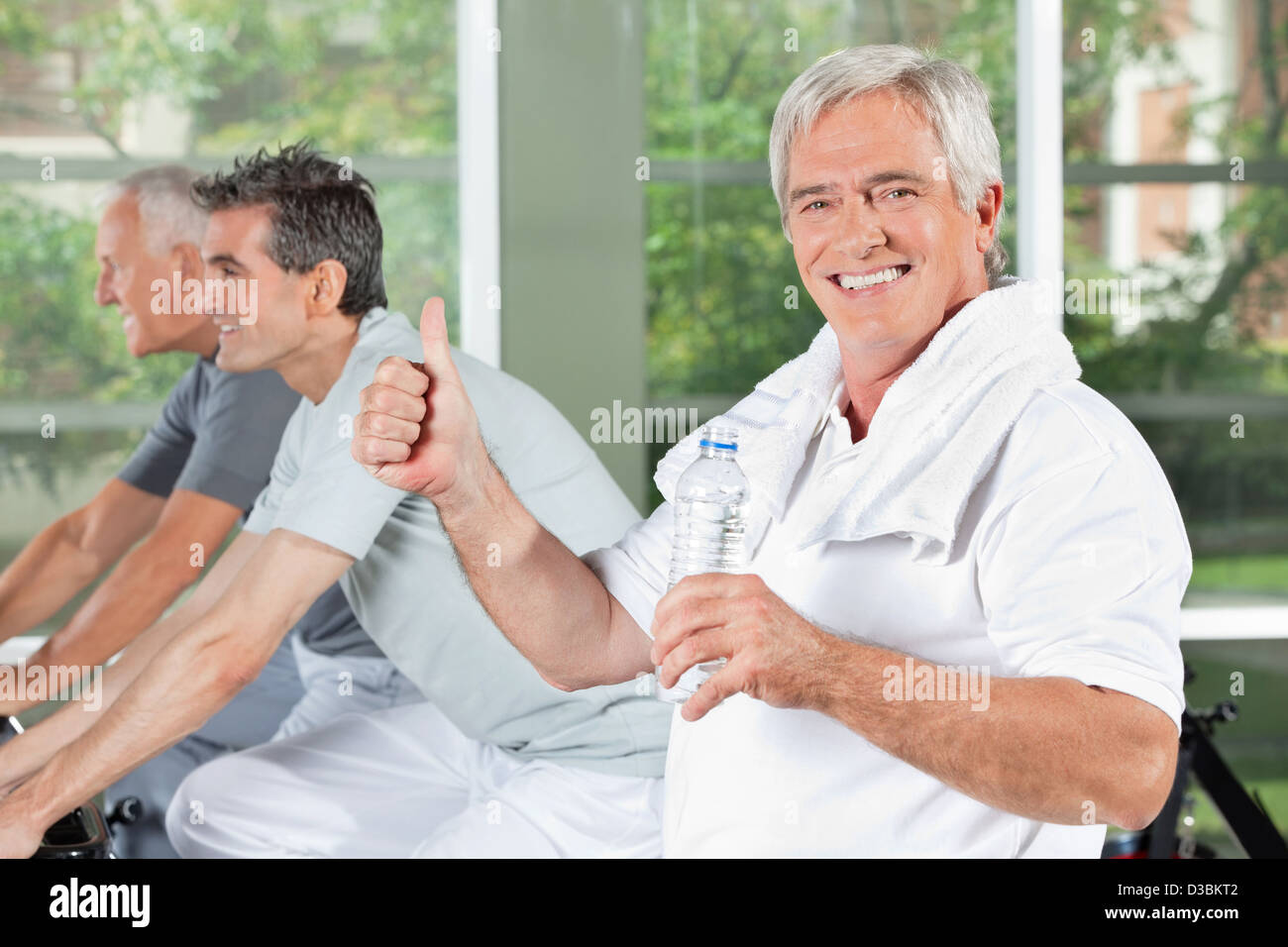 Happy senior man with water bottle in gym holding thumb up Stock Photo ...