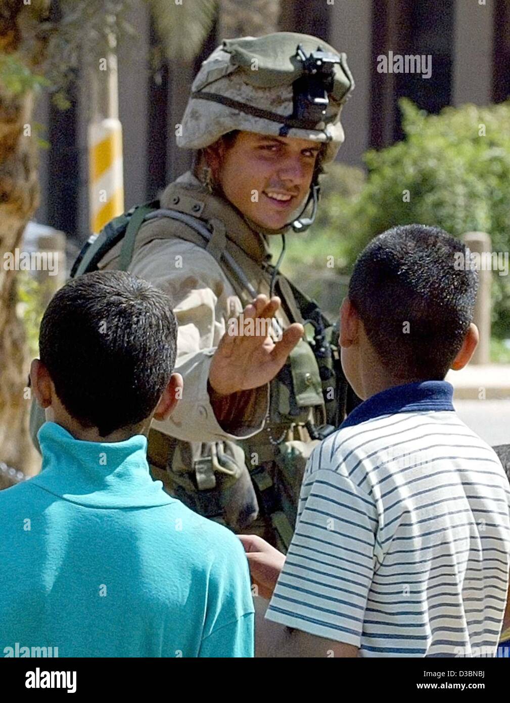 (dpa) - A US soldier greets two Iraqi boys in Baghdad, 11 April 2003. The entire medical care in Baghdad has broken down, Red Cross officials said. Hospitals and clinics in the Iraqi capital are closed, the patients have either fled or are left on their own. The rising temperature increases the risk Stock Photo
