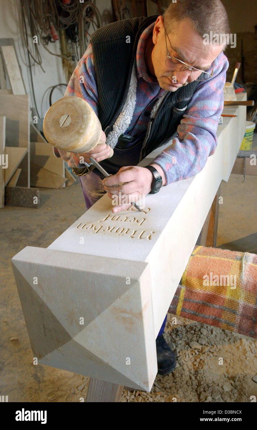 (dpa) - Norbert Kuttig chisels letters into a column made of nature stone in his workshop in Muenchenbernsdorf, eastern Germany, 7 April 2003. Apart from the production of traditional pieces such as window sills, steps and kitchen boards Kuttig also specialises in the restoration of architectural de Stock Photo