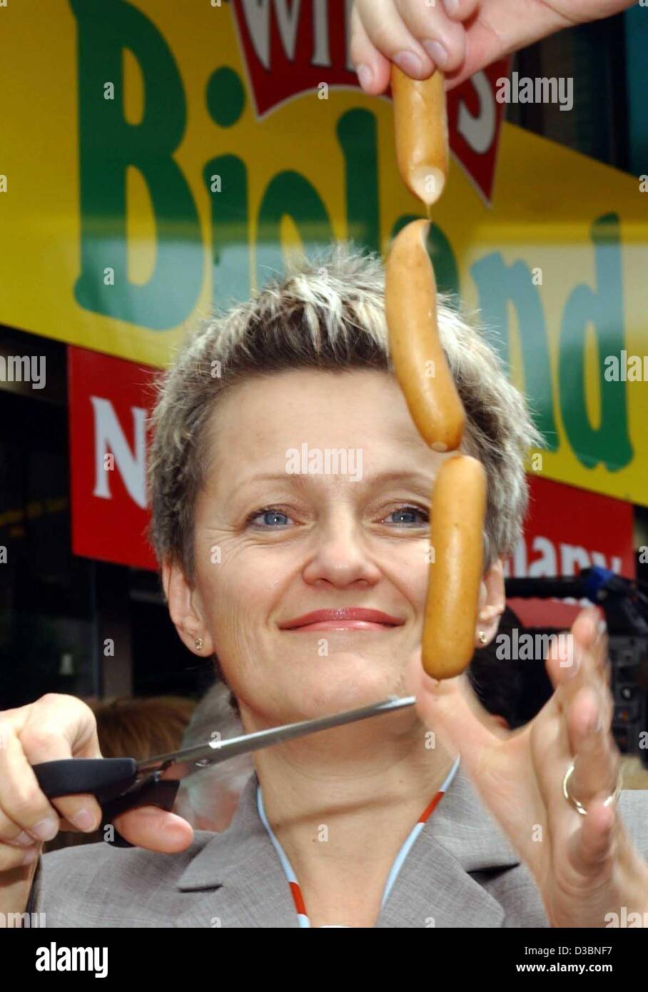 (dpa) - Renate Kuenast (Alliance 90/The Greens), German Minister for Consumer Protection, Food and Agriculture, uses a pair of scissors to cut sausages off a chain, Berlin, 21 May 2003. In the background is the 'Bioland' label, a cooperative of ecological farmers. According to the operator 'Witty's' Stock Photo