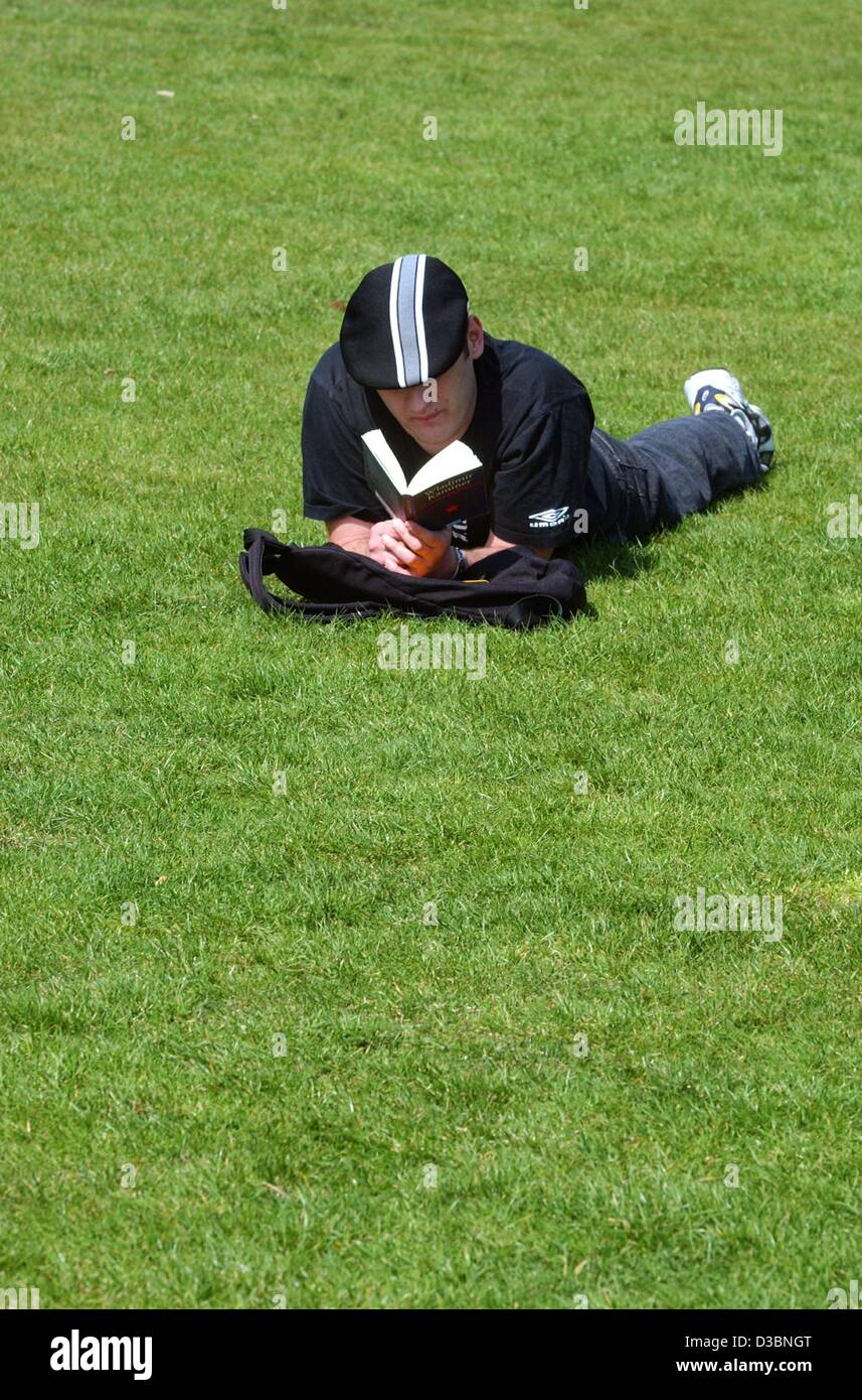 (dpa) - A man is lying on a lawn reading a book, Berlin, 23 April 2003. This is 'World Book and Copyright Day' and a symbolic date for world literature because on 23 April 1616, Cervantes, Shakespeare and Inca Garcilaso de la Vega all died. By celebrating this day throughout the world, UNESCO seeks  Stock Photo