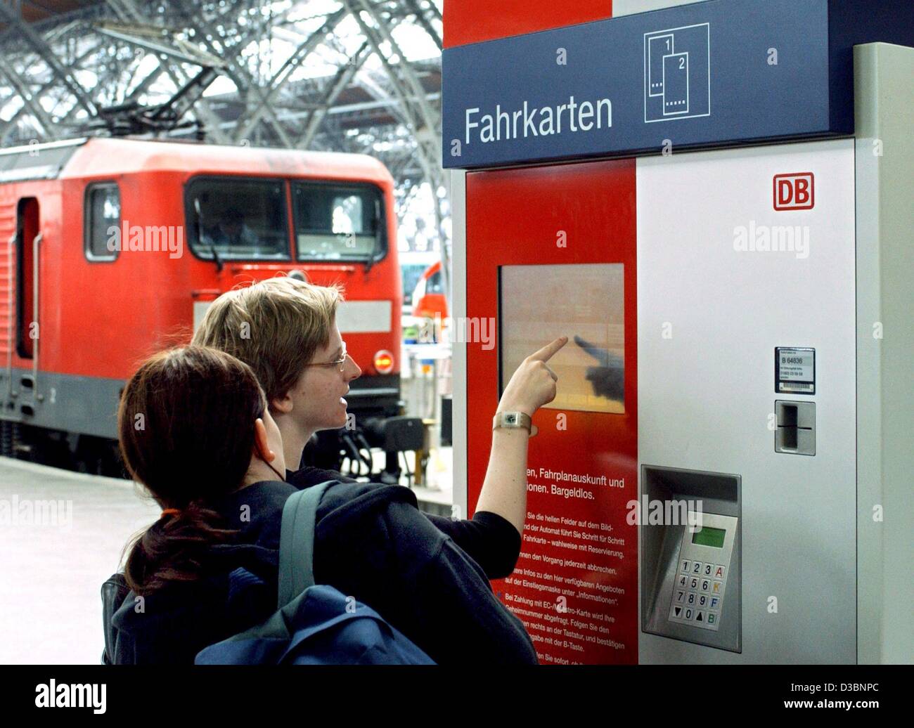 (dpa) - Two travellers buy railway tickets (Fahrkarten) from a ticket vending machine at the central station in Leipzig, Germany, 19 May 2003. The German railway corporation Deutsche Bahn AG will reconsider their new price system for tickets, which was introduced last December. Since, the turnover i Stock Photo