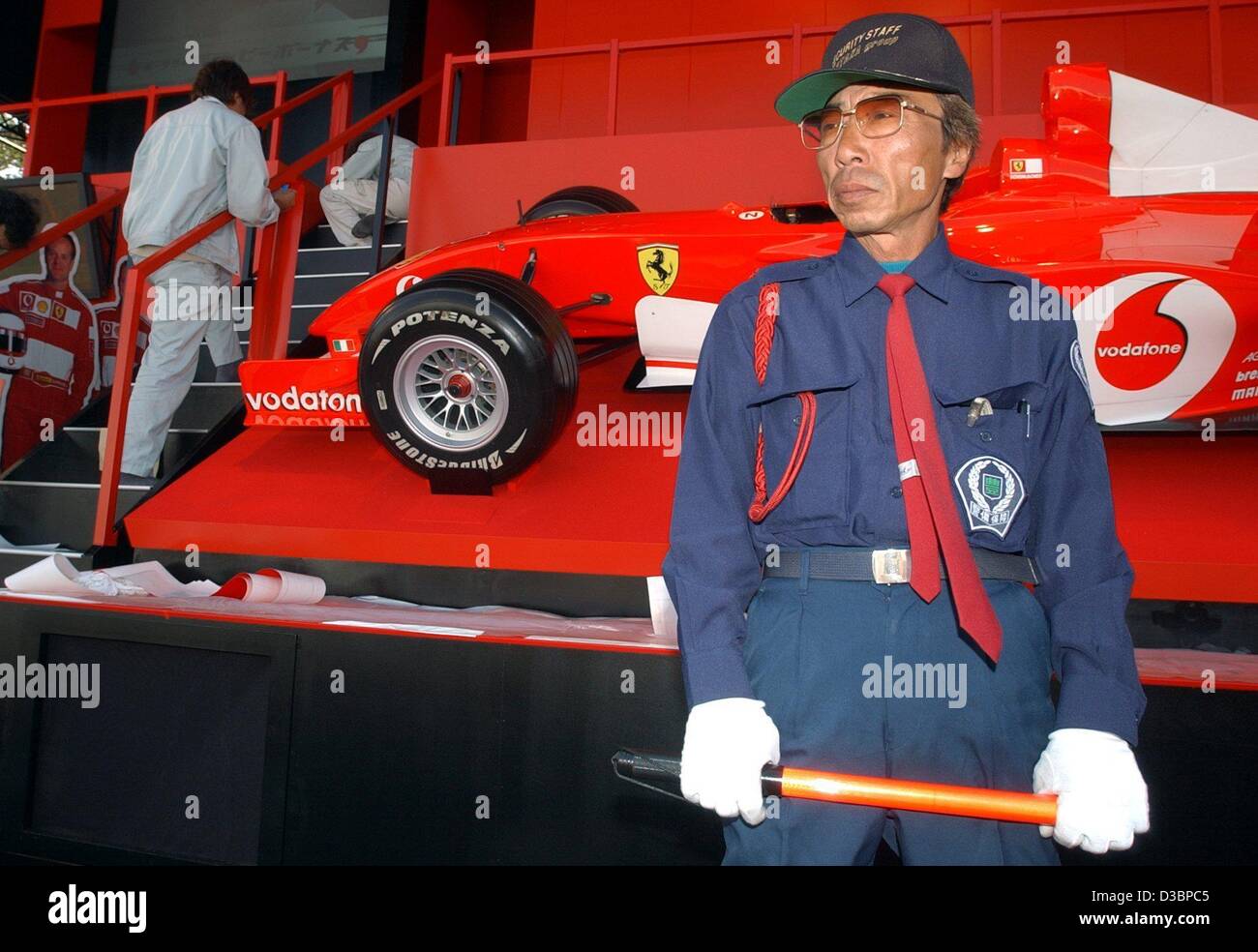 (dpa) - A Japanese security guard protects a Ferrari race car on the race track in Suzuka, Japan, 9 October 2003. The decisive race of the formula one world championship will take place in Suzuka, around 300 kilometres south of Tokyo on 12 October 2003. Stock Photo