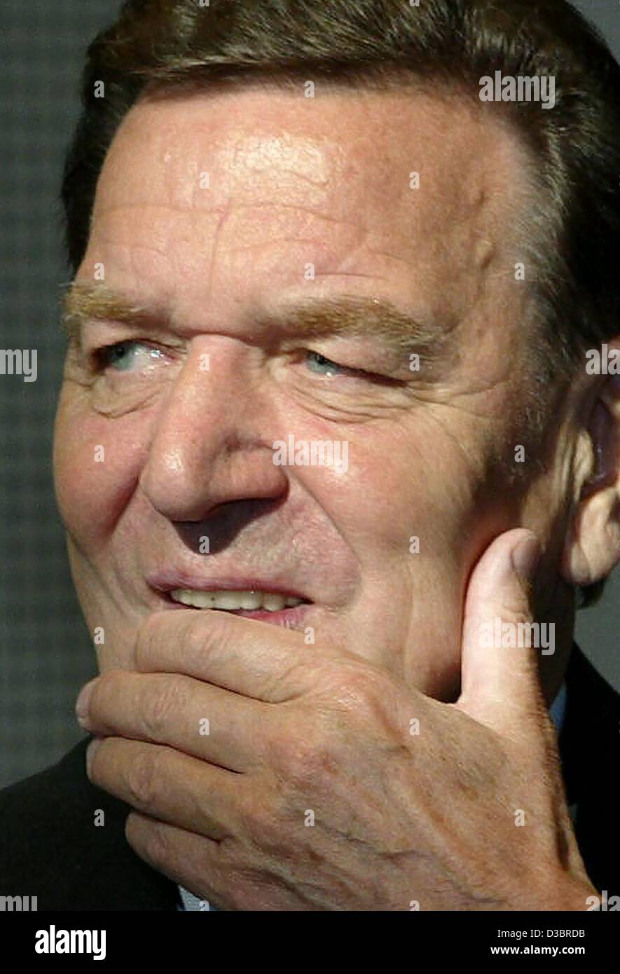 (dpa) - German Chancellor Gerhard Schroeder touches his chin during a birthday celebration for Klaus Wowereit, the current mayor of Berlin, at the House of Representatives in Berlin, 1 October 2003. Stock Photo