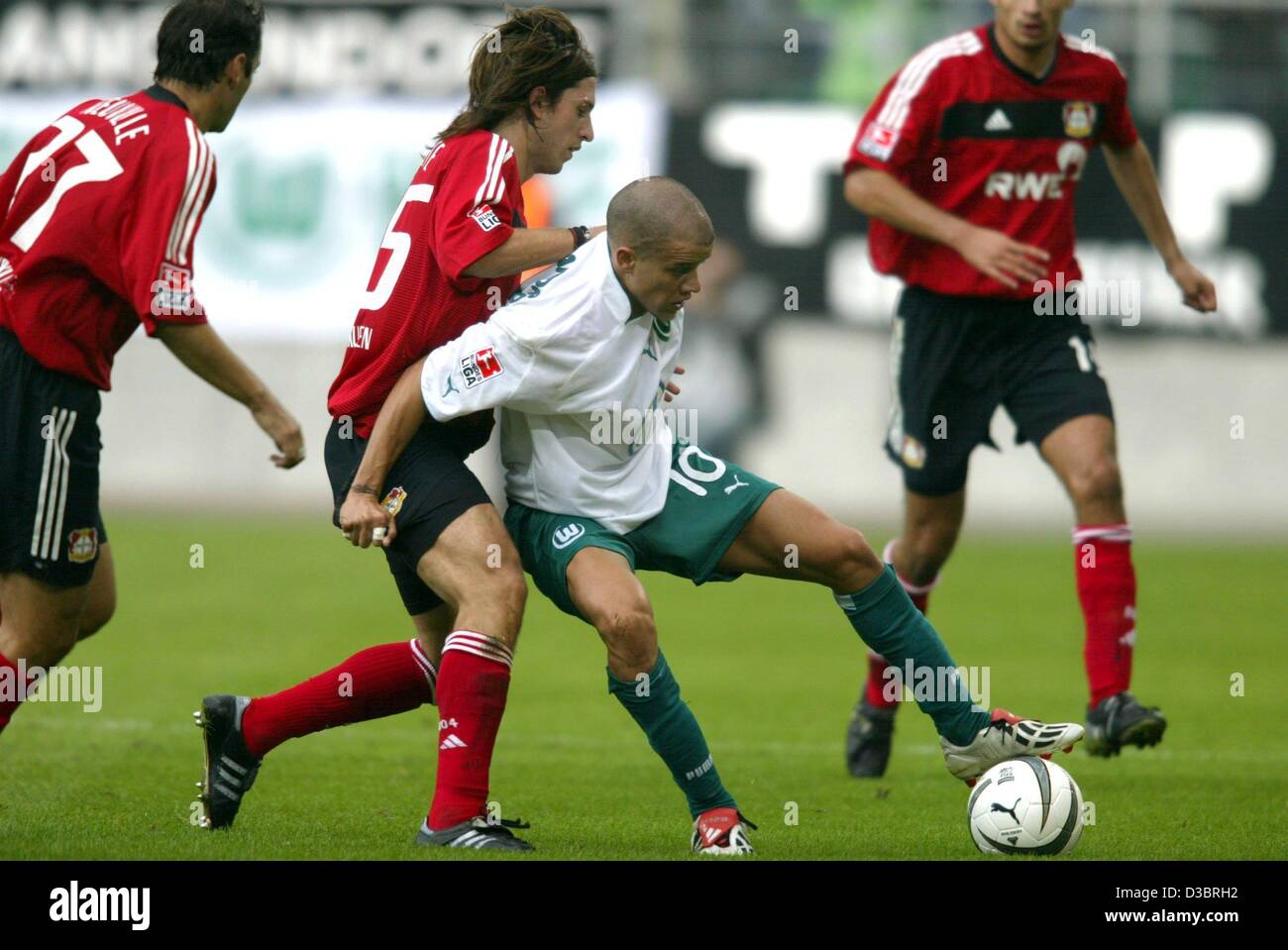 (dpa) - Wolfsburg's Argentina midfielder  Andres d'Alessandro (C) has the ball and struggles to defend it against Leverkusen's Argentine defender Diego Placente (2nd from L) while Leverkusen's forward Oliver Neuville (L) looks on during the Bundesliga soccer game VfL Wolfsburg against Bayer 04 Lever Stock Photo